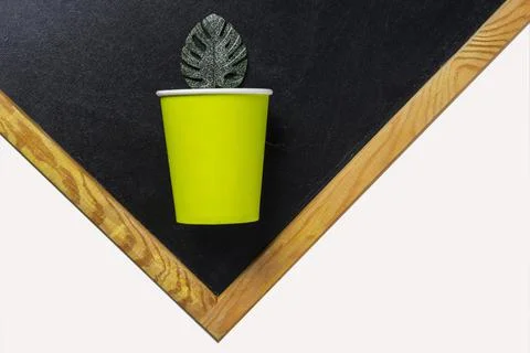 Creative minimalistic composition,a paper cup and a green leaf on a black and Stock Photos