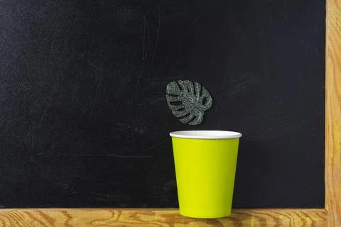 Creative minimalistic composition,a paper cup and a green leaf on a black bac Stock Photos