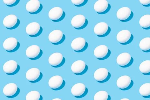 Creative minimalistic pattern - white chicken eggs on a blue background Stock Illustration