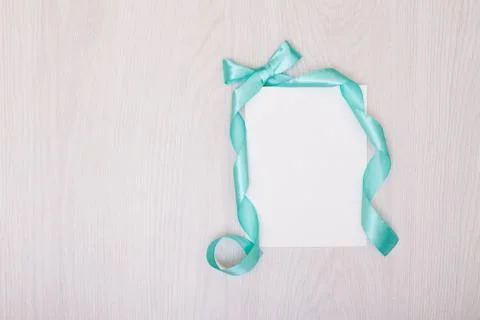 Creative mock up with ablank piece of paper. blue ribbon and bow. Stock Photos