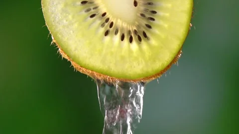 Creative mockup of sliced kiwi slice and water. Splashes on green background. Stock Footage 248782306
