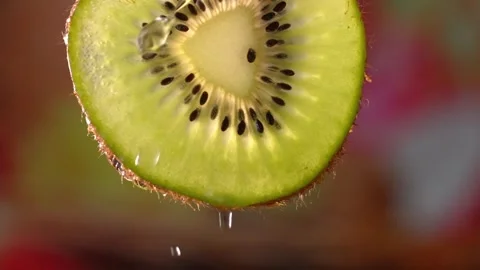 Creative mockup of sliced kiwi slice and water. Splashes on green background. Stock Footage 248892574