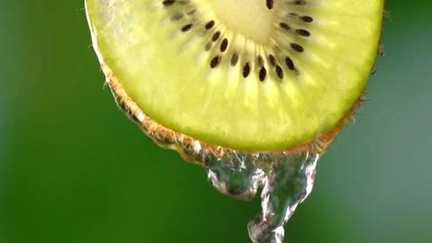 Creative mockup of sliced kiwi slice and water. Splashes on green background. Stock Footage 248893144