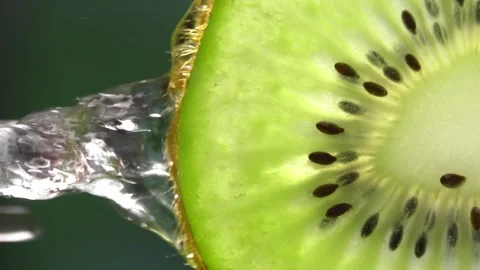 Creative mockup of sliced kiwi slice and water. Splashes on green background. Stock Footage 251912718