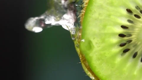 Creative mockup of sliced kiwi slice and water. Splashes on green background. Vídeo Stock 251912848