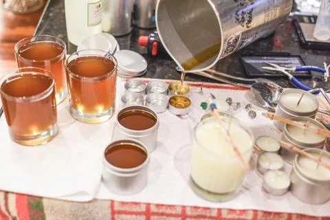 Creative occupation of candle making showing the pouring of liquid wax into j Stock Photos
