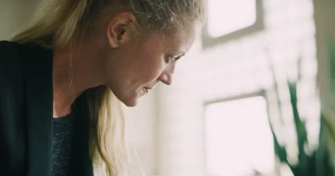In a creative office, an associate checks on her colleague's paperwork at her de Stock Footage 199460261