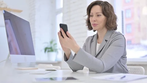 Creative Old Woman using Smartphone on Office Desk Vidéo 123336446
