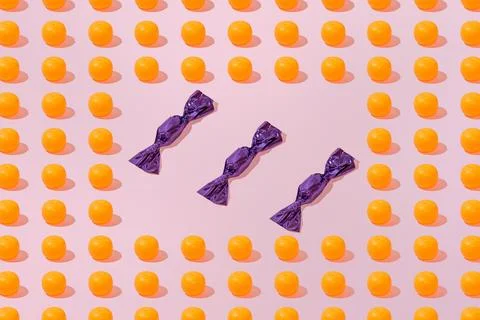 Creative orange and candy pattern flat lay on pastel pink background minimali Stock Photos