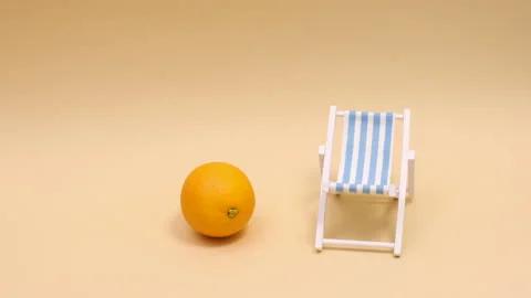 Creative orange with umbrella come on sun lounger. Stop motion Stockbeeldmateriaal 158860660