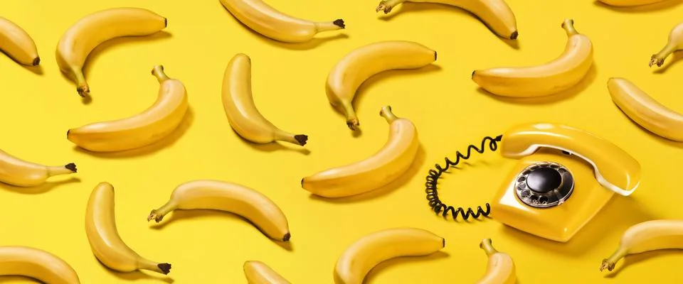 Creative pattern bananas and old yellow phone with hard shadows pattern on ye Fotos Stock