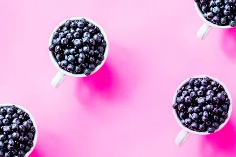 Creative pattern of blueberries in white cups on bright background.Seamless Stock Photos