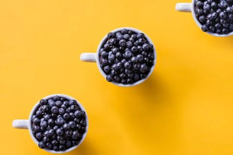 Creative pattern of blueberries in white cups on bright background.Seamless Foto stock