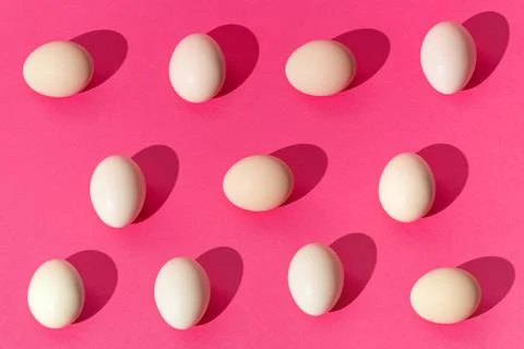 Creative pattern done with white eggs on trendy pink background. Minimal east Stock Photos
