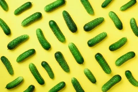 Creative pattern of fresh green cucumbers on yellow background. Top view. Copy Stock Photos