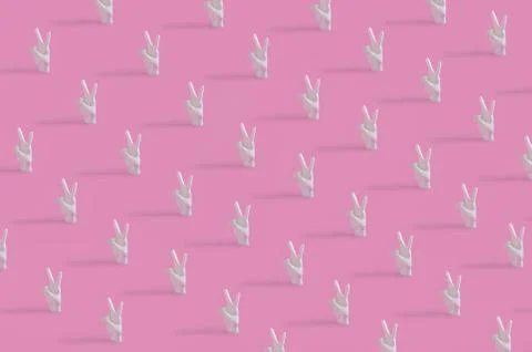 A creative pattern with human hand showing two fingers up on pastel pink back Stock Photos