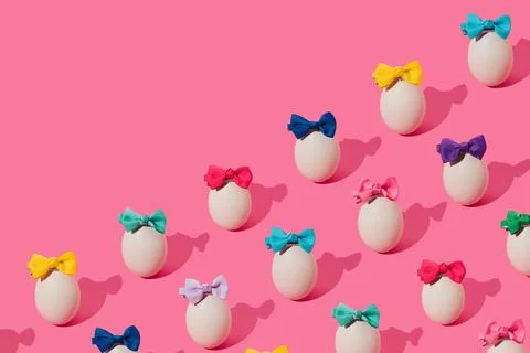 Creative pattern made with eggs and colorful bows on trendy pink background.  Stock Photos