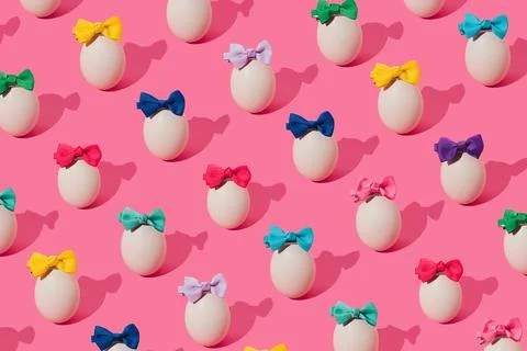 Creative pattern made with eggs and colorful bows on trendy pink background.  Stock Photos