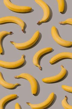 Creative pattern made with yellow bananas on a gray background. Stock Photos