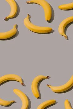 Creative pattern made with yellow bananas on a gray background. Stock Photos