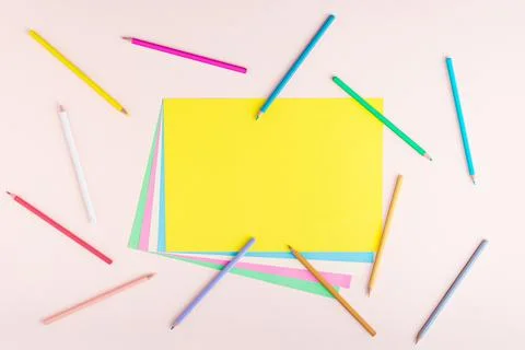 Creative pattern of multicolored pencils and papers in pastel colors on a lig 스톡 사진