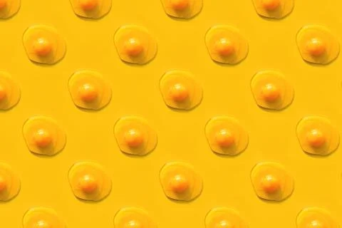 Creative pattern with raw eggs with yolks on yellow background. 스톡 사진
