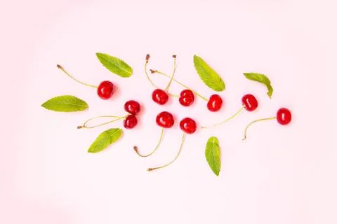 Creative pattern of red cherries on pink background. Top view with copyspace Stock Photos