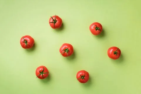 Creative pattern of red tomatos on green background. Top view. Copy space Stock Photos
