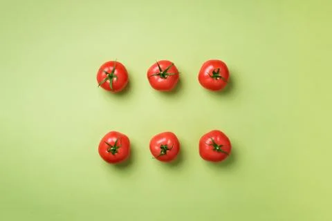 Creative pattern of red tomatos on green background. Top view. Copy space Stock Photos