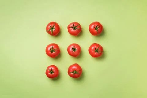 Creative pattern of red tomatos on green background. Top view. Copy space Stock Photos