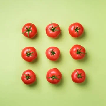 Creative pattern of red tomatos on green background. Top view. Copy space 스톡 사진