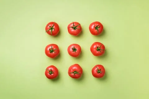 Creative pattern of red tomatos on green background. Top view. Copy space Stock Photos