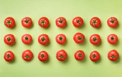 Creative pattern of red tomatos on green background. Top view. Copy space Stock Photos