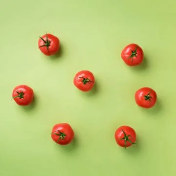 Creative pattern of red tomatos on green background. Top view. Copy space Stock Photos