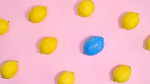 Creative pattern with yellow lemons and one blue on pastel pink background. F Stock Photos