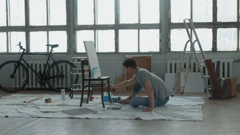 Creative person draws in bright studio with a large window. 스톡 동영상 125613604