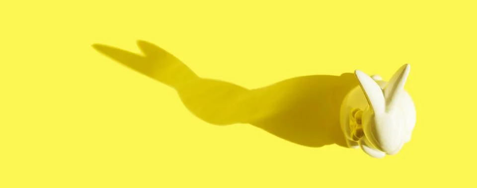 Creative photo. Ceramic Easter bunny on a yellow monochrome background, the Stock Photos