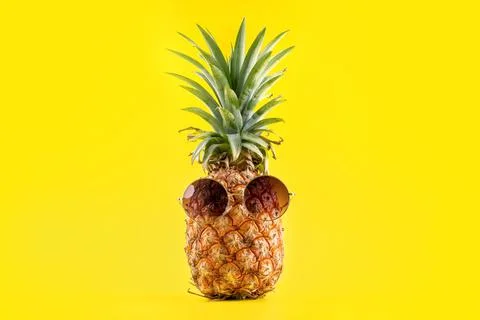 Creative pineapple looking up with sunglasses and shell isolated on yellow ba Foto stock
