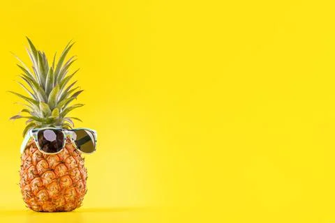 Creative pineapple looking up with sunglasses and shell isolated on yellow ba Stock Photos