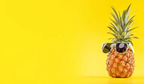Creative pineapple looking up with sunglasses and shell isolated on yellow ba Stock Photos