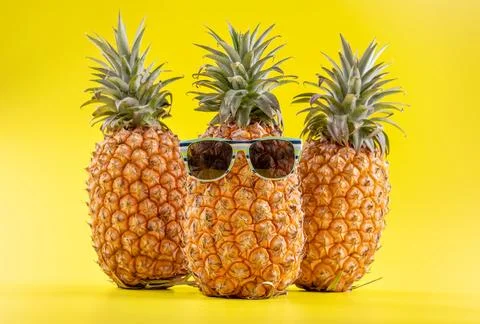 Creative pineapple looking up with sunglasses and shell isolated on yellow .. Stock Photos
