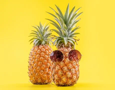 Creative pineapple looking up with sunglasses and shell isolated on yellow .. Stock Photos