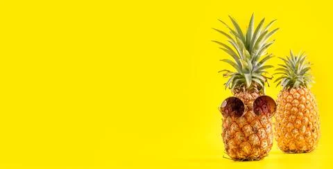Creative pineapple looking up with sunglasses and shell isolated on yellow .. Stock Photos