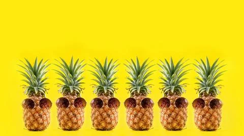 Creative pineapple looking up with sunglasses and shell isolated on yellow .. Stock Photos
