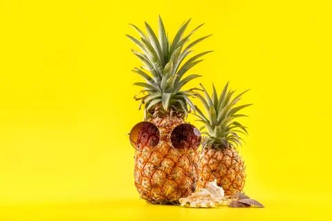 Creative pineapple looking up with sunglasses and shell isolated on yellow .. Stock Photos