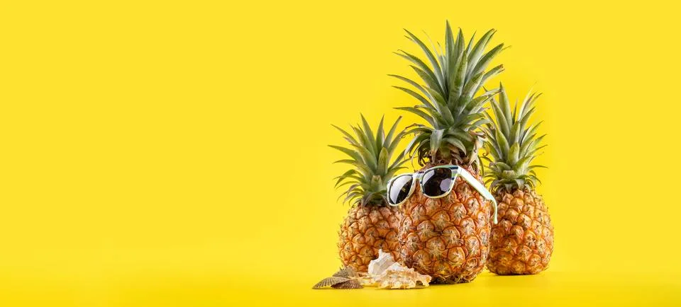 Creative pineapple looking up with sunglasses and shell isolated on yellow .. Stock Photos