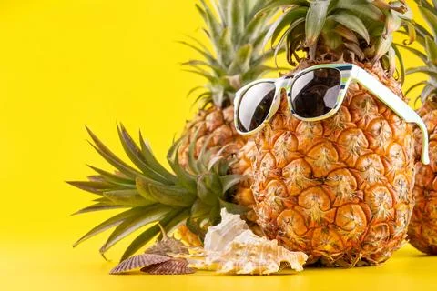 Creative pineapple looking up with sunglasses and shell isolated on yellow .. Stock Photos