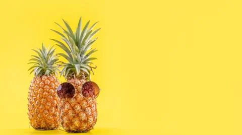 Creative pineapple looking up with sunglasses and shell isolated on yellow .. Stock Photos