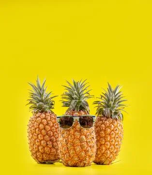 Creative pineapples with sunglasses isolated on yellow background, summer v.. Stock Photos