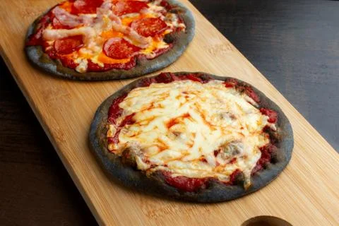 Creative pizza on black dough, two pieces on the board. Stock Photos